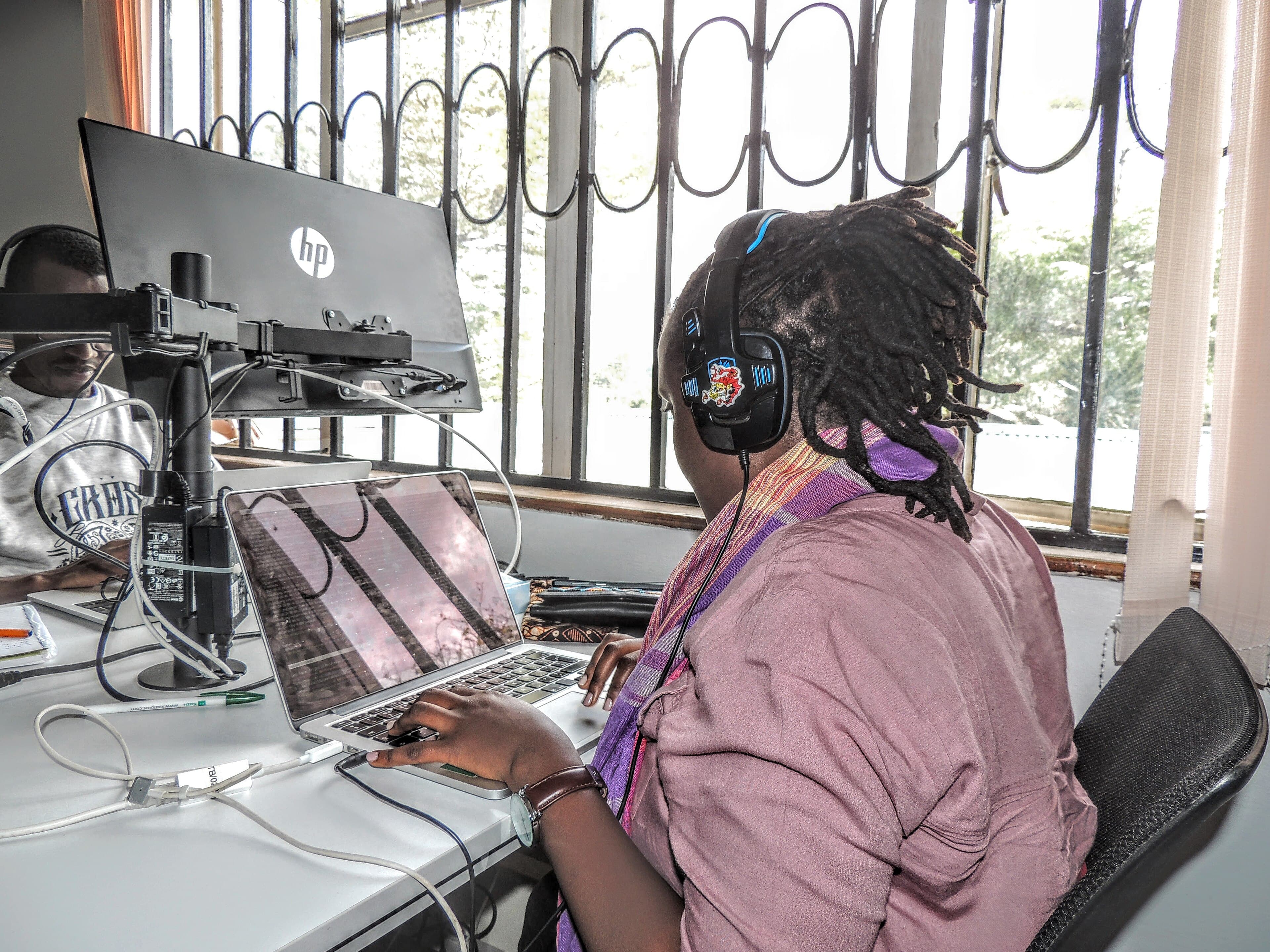 Engineer with headphones working on a laptop at a shared desk