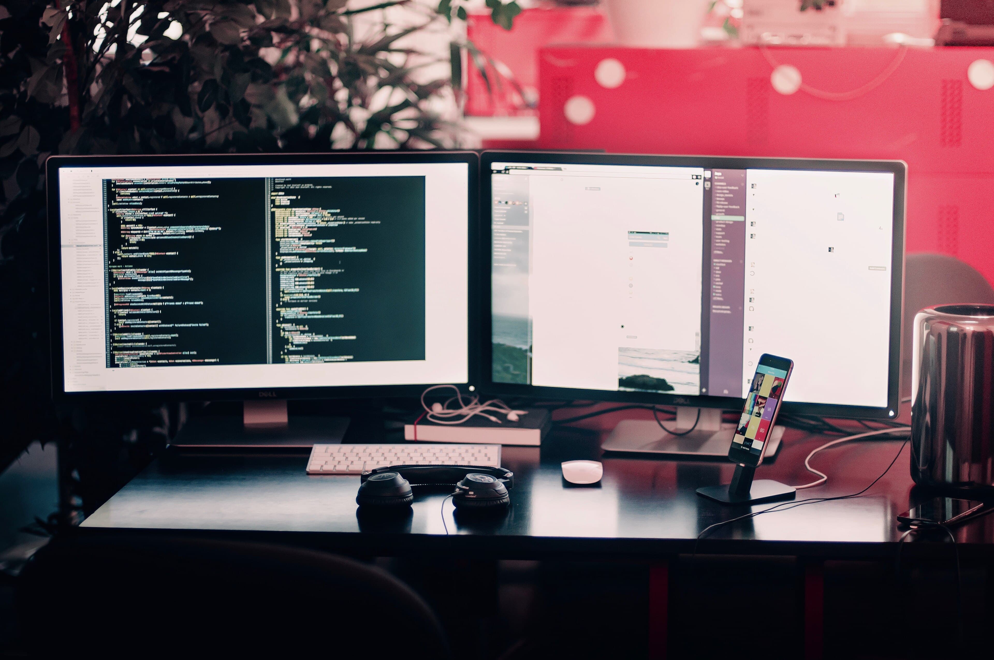 Two monitors showing code on a dark desk